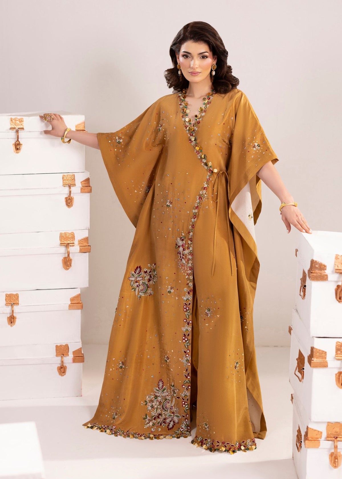 Woman wearing a mustard yellow embroidered dress against a white background