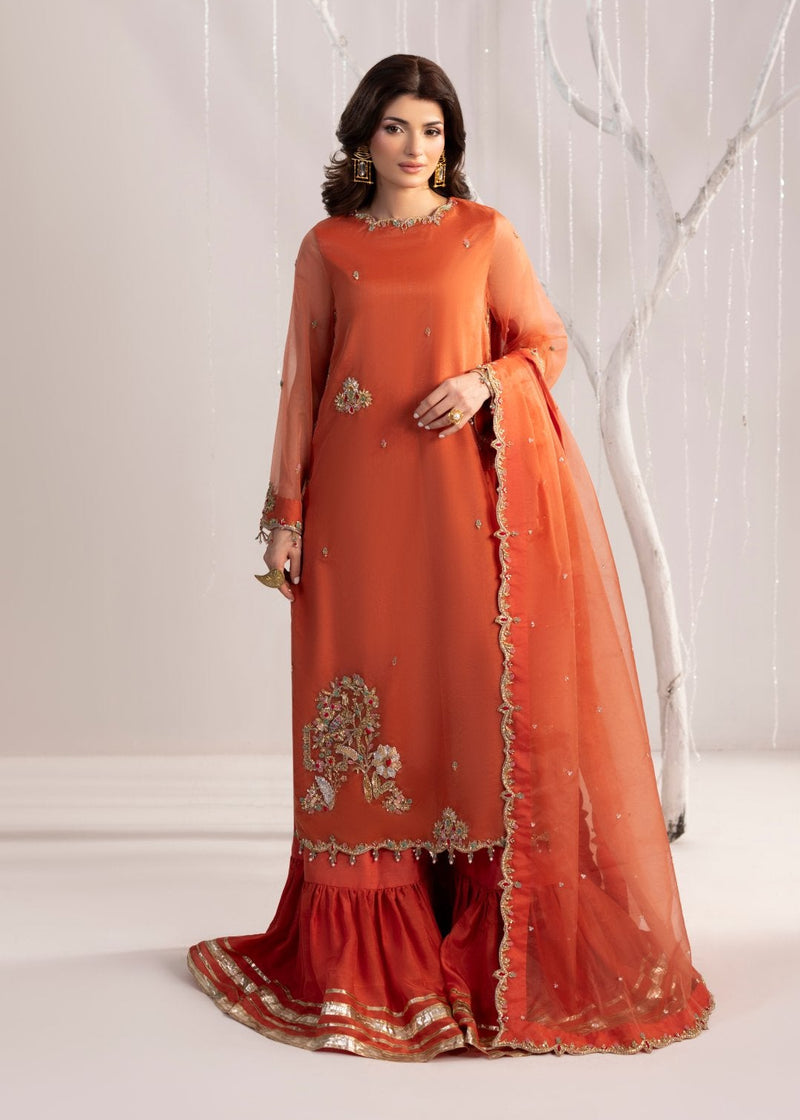 Woman wearing an orange traditional outfit with intricate designs against a white background